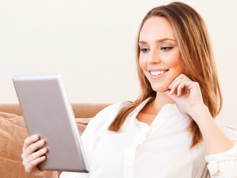 woman sitting on couch with tablet